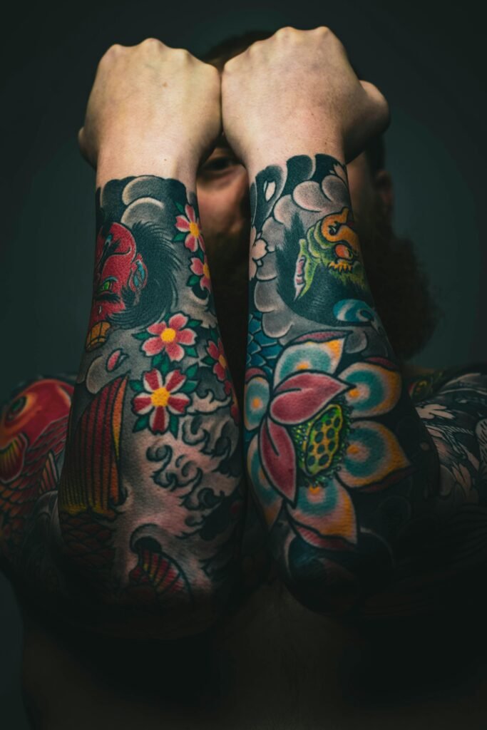 Vibrant forearm tattoos featuring flowers and koi fish showcased in an artistic pose.
